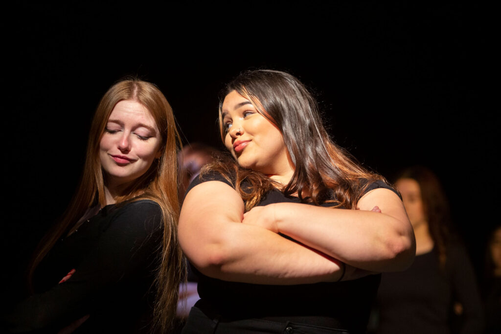 Two young female performers with a black background