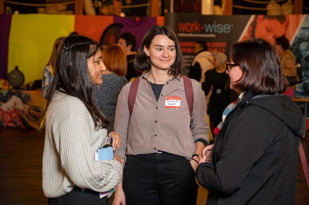 Three diverse young women talking and smiling at a conference