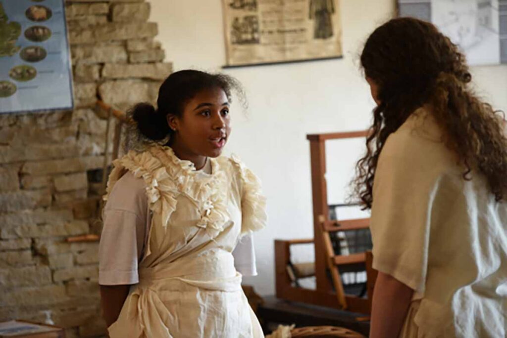 Two school children taking part in a performance with Victorian dress