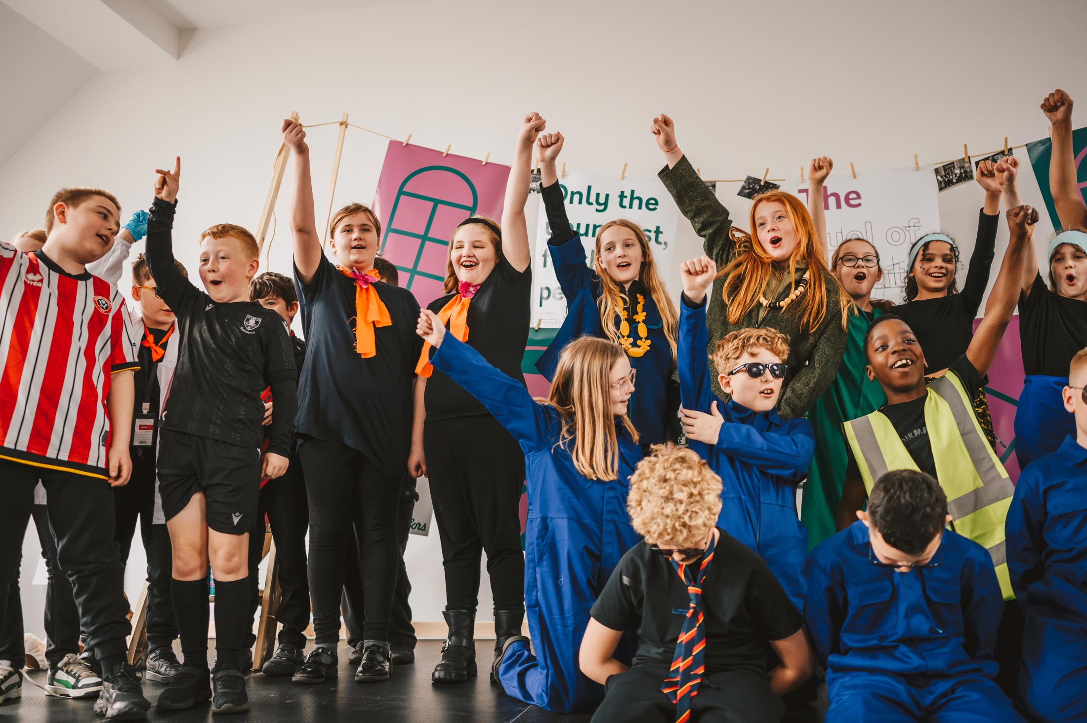 Group of children on stage, cheering and with their hands in the air